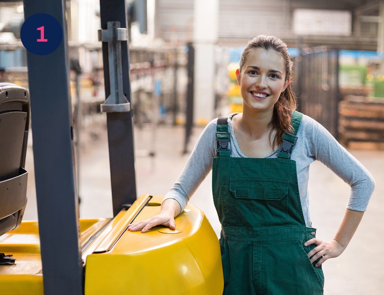 A woman working in a factory smiles at the camera
